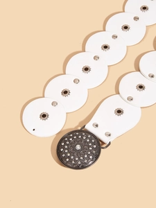 Detail of western retro belt with white leather discs and rhinestone studded silver buckle