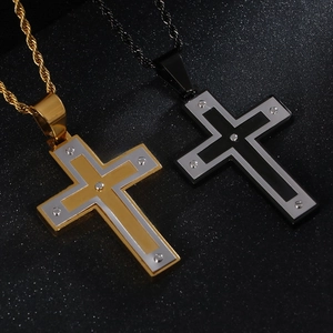 Détail de pendentifs croix en acier bicolore or et noir avec chaînes de torsion