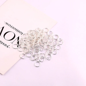 Bulk silver jump rings on decorative paper for handmade jewelry making and DIY projects