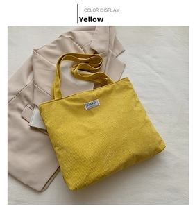 Detail of yellow corduroy tote bag with fashion label on a soft neutral background