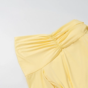 Close-up of yellow knitted dress showing elegant ruched pleats and fabric texture