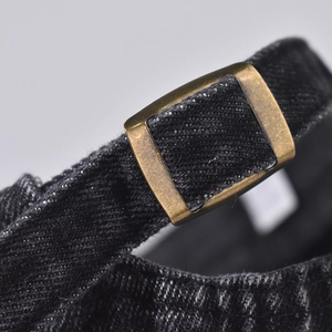 Detail of vintage brass adjustment buckle on heavy-weight black denim cap fabric