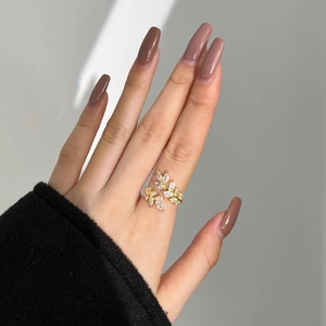 Detail of elegant gold leaf ring with zircon inlay worn on hand with soft lighting