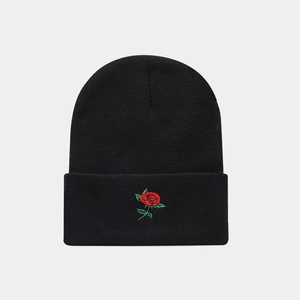 Close-up of red heart embroidery on the folded brim of a black knitted beanie hat