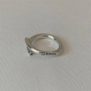 Macro detail of silver adjustable smile ring with engraved lettering on white surface