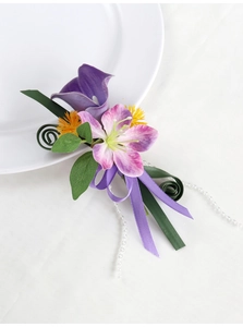 Detail of purple calla lily and lily boutonniere with silk ribbons and green leaves