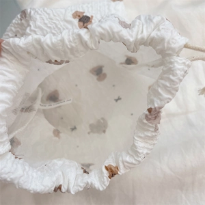 Detailed view of white seersucker drawstring bag with brown bear print and inner lining
