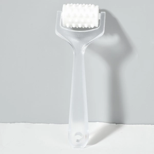 Close-up of a white toothed roller head on a translucent handheld massage tool