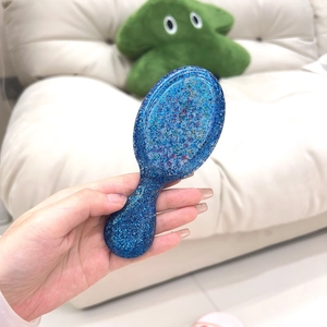 Close-up of portable blue glitter hairbrush with compact handle and massage cushion