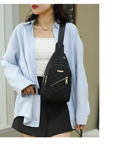 Detail of black quilted nylon chest bag with golden zippers and adjustable wide strap