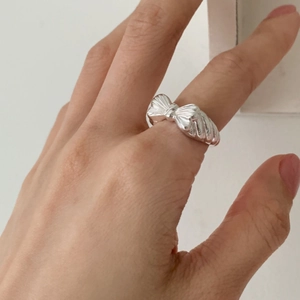Close-up of polished 925 sterling silver bow ring worn on a finger in a natural setting