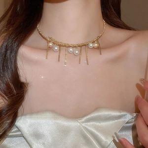 Close-up of a gold choker featuring elegant pearls and long tassel pendants on a model