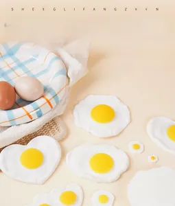 Vista detallada de modelos realistas de huevos fritos de PVC en forma de corazón en un plato