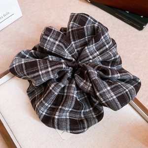 Detailed view of a large plaid fabric scrunchie with soft brown and beige cotton textures