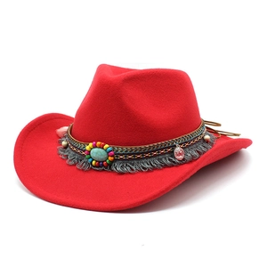 Détail d'un chapeau de cowboy en feutre rouge avec perles colorées et pompons