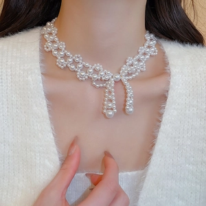 Close-up of elegant pearl choker with a bow pendant on model neck