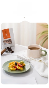 Detail einer nordischen Keramik-Kaffeetasse mit grünem Griff und passendem Dessertteller