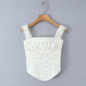 Detail van een witte camisole met bloemenprint, kanten randen en gesmokte textuur
