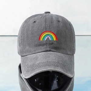 Close-up of rainbow embroidery on a grey washed denim baseball cap with visible stitching