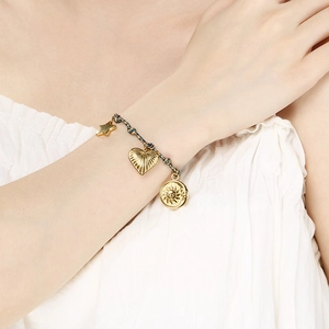 Close-up of bohemian woven bracelet with gold sun, heart, and star charms on wrist