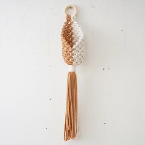 Detail of handmade macrame hanging basket with natural wooden ring and long cotton tassels