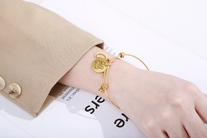 Detail of adjustable gold bangle with celestial moon and star charms worn on wrist