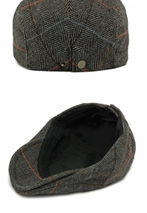 Detail of grey herringbone wool ivy cap with orange accents and metal brim snap