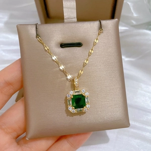 Detail shot of a luxury gold necklace featuring a square green emerald and white diamonds