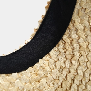 Close-up of natural straw weave texture with black fabric edge on a sun hat