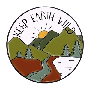 Detail of round Keep Earth Wild enamel pin featuring mountain and river landscape