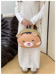 Detail of a brown cartoon animal backpack for kids with a hard shell and strap handle