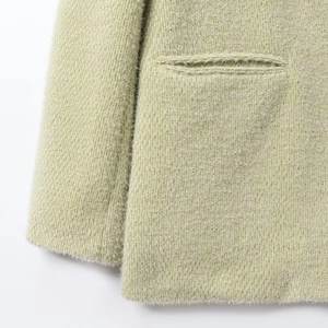 Detailopname van het limoengroene gebreide jasje met fluwelen textuur en zakdetail