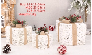 Close-up of white rattan Christmas gift boxes with pine cones and burlap bows
