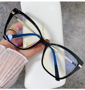 Close-up of black butterfly frame glasses with gold metal temples held in hand