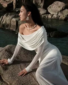 Detail of elegant white off-shoulder ruched dress with sheer mesh sleeves and slim fit design