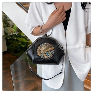 Detail of black vintage shell bag featuring round elephant pattern metal relief and chain