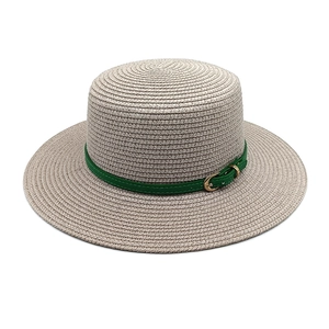 Détail du chapeau canotier beige montrant la texture tressée et le ruban en cuir vert