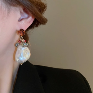 Detail of baroque pearl earring with dark crystal on a model wearing black suit