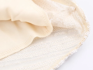 Macro detail of the elegant beige lace mesh hem with shimmering white sequin embroidery