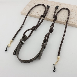 Detail of dark brown braided eyewear chain with leather accents and gold metal clasps