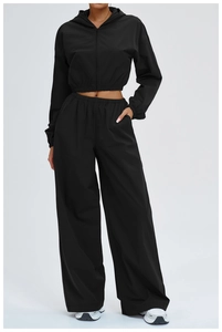 Detail of a black hooded sports jacket and high-waist wide-leg pants on a model