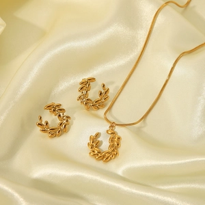 Detailed view of golden leaf jewelry set including necklace and earrings on beige silk