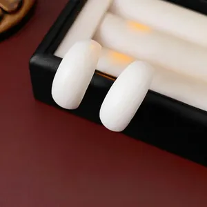 Minimalist white C-shaped wooden stud earrings displayed on a professional jewelry stand