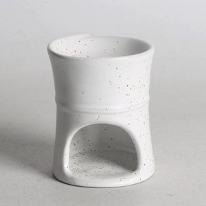 Close-up of a white ceramic aroma burner with brown spots and an arched candle opening