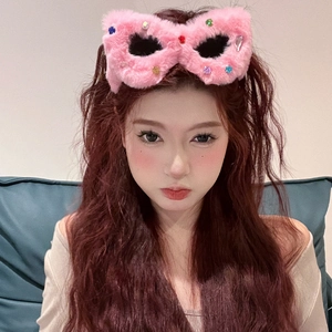 Pink plush cat eye heart sunglasses with colorful rhinestone embellishments on a model