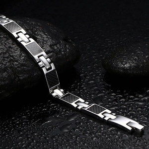 Armband aus Titanstahl mit schwarzen Carbon-Einlagen auf nassem Steinhintergrund