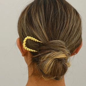 Detailed view of a gold U-shaped metal hair pin with textured design on elegant updo