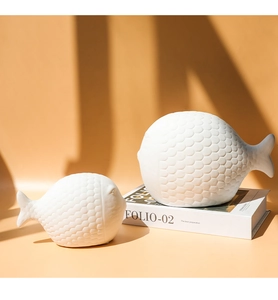 Detalle de figuras de peces de cerámica blanca mate con relieve de escamas en 3D