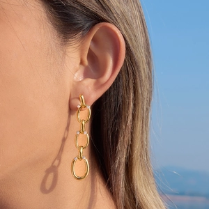 Boucles d'oreilles pendantes en acier doré avec maillons ovales et zircons sur mannequin