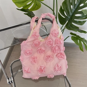 Detailed view of pink shoulder bag featuring 3D fabric rose floral accents and texture